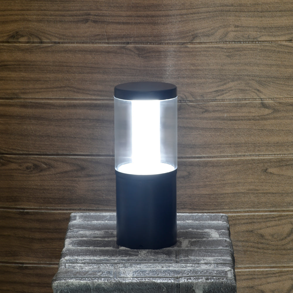 Cylindrical lamp with clear cover and black base on a wooden background