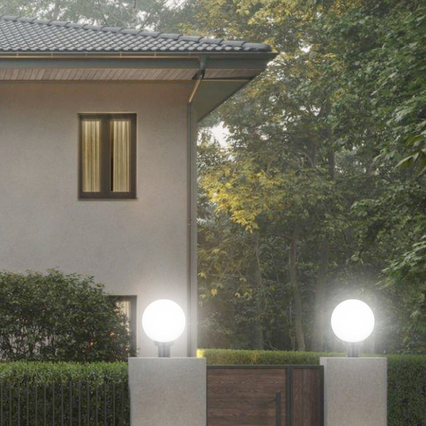 Globe-shaped entrance lamp on gate pillars lighting modern house entry